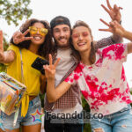 happy young company of emotional smiling friends walking in park with photo camera, man and women having fun together, colorful summer hipster fashion style, talking, smiling